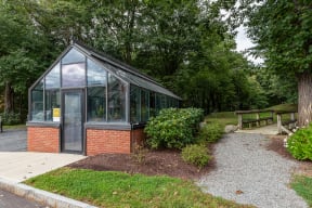 a greenhouse in a park with trees and a sidewalk