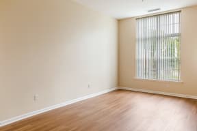 an empty living room with wood floors and a window