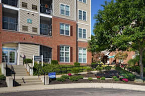 an apartment building with stairs and a garden in front