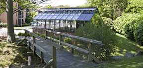 a greenhouse in a park with a wooden bridge