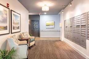 a lobby with two chairs and a wall of mailboxes