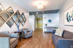 a living room with couches and chairs and a hallway in the background