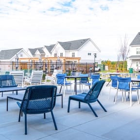 a patio with blue chairs and tables and houses in the background