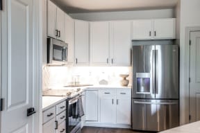 a white kitchen with stainless steel appliances and white cabinets