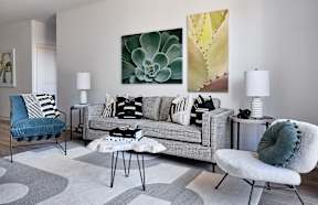a living room with a gray couch and pillows and a table