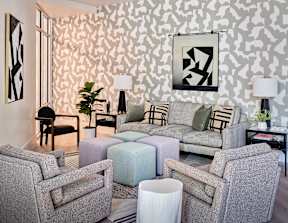 a living room with couches and chairs and a geometric wallpaper