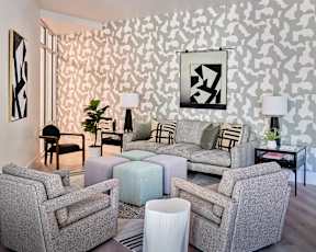 a living room with gray couches and chairs and a geometric wallpaper