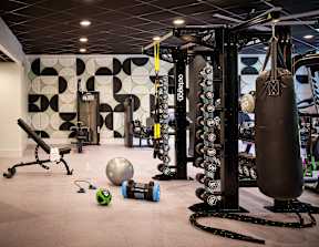 a gym with weights and dumbbells on the floor and a wall of mirrors