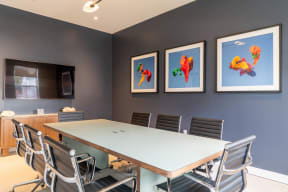 a conference room with a long table and chairs and three paintings on the wall