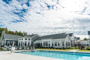 a swimming pool with lounge chairs and a building in the background