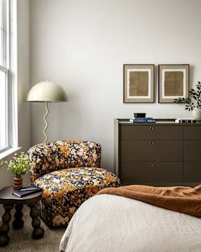 a bedroom with a chair and a lamp and a dresser