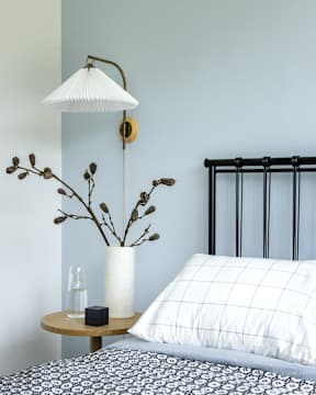 a bedroom with a bed and a lamp and a vase with flowers