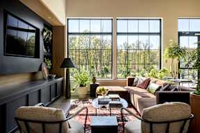 a living room with a couch and chairs and large windows
