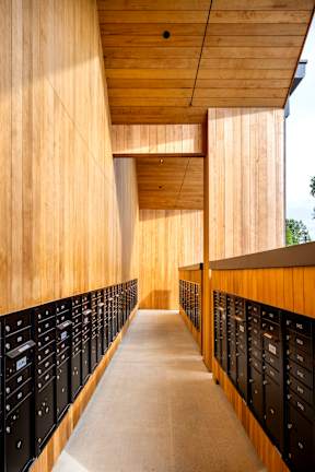 A long hallway with black lockers on the side and wood paneling on the walls.