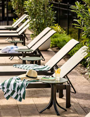 A sun lounger with a hat and a striped towel on it.