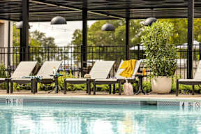 A pool with a black fence and a yellow towel on a chair.