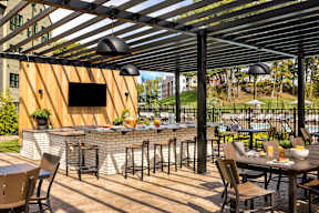 A patio with a bar and chairs under a black awning.