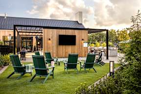 A wooden building with a black roof and a row of green chairs in front of it.