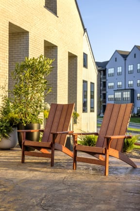two wooden chairs sitting on a patio in front of a building