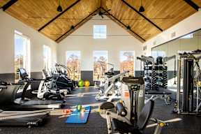 A gym with a variety of exercise equipment including treadmills, stationary bikes, and weight machines.