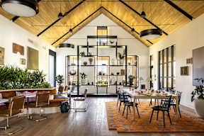 A modern dining room with a wooden ceiling and a large table surrounded by chairs.