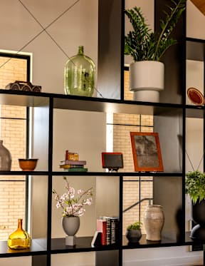 A shelf with various decorative items including vases, books, and a potted plant.
