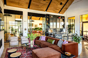 A living room with a brown couch and a red rug.