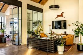 A living room with a glass door, a brown horse decoration, and a black and white striped couch.
