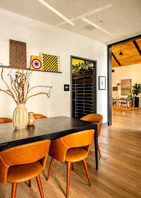 A dining room with a black table and brown chairs.