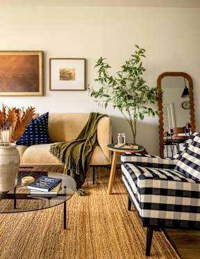 A living room with a checkered sofa and a glass coffee table.