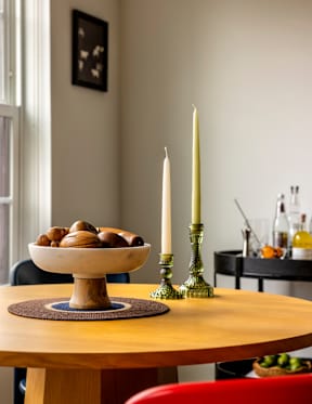 A wooden table with a bowl of snacks and two candles.