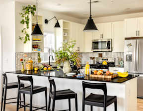 A kitchen with black chairs and a black countertop.