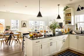 A kitchen with white cabinets and a black countertop.