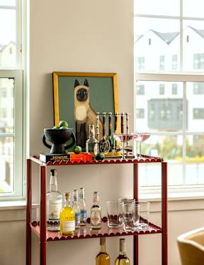 A red shelf with bottles and glasses on it.