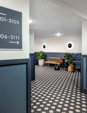 A hallway with a bench and potted plants.