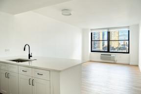 an empty kitchen with white cabinets and a large window