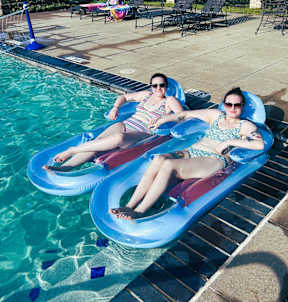 Two women are lounging on a pool float.