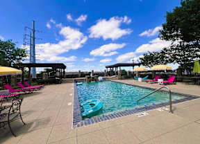 A pool area with a blue pool and yellow umbrellas.