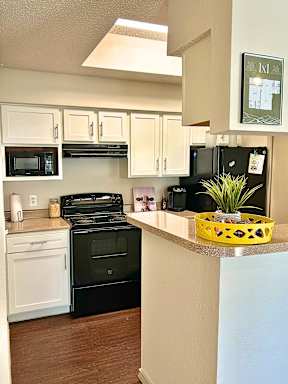 A kitchen with black appliances and white cabinets.
