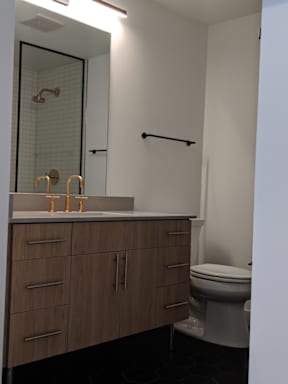 A bathroom with a toilet, sink, and a mirror.