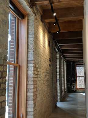 A long hallway with brick walls and wooden beams on the ceiling.