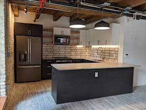 A kitchen with a black countertop and a brick wall.