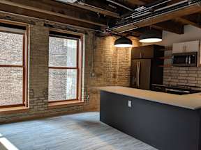 A kitchen with a black counter and a brick wall.