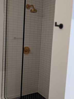 A white door with a black handle and a gold shower head.