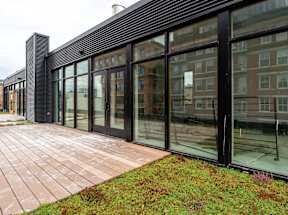 A modern building with a glass facade and a brick walkway in front.