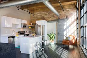 A kitchen with a brick wall and a wooden floor.