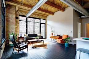 A living room with a black couch and a wooden chair.