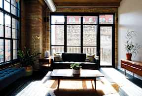 A living room with a black couch and a large window.
