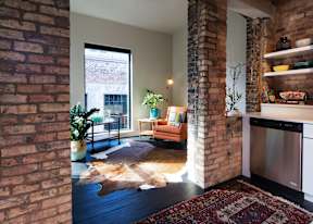 A living room with a cowhide rug and a brick wall.