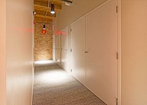 A hallway with white doors and a brick wall.